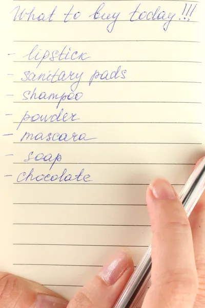 Woman's hand holding a notebook with a shopping list close-up — Stock Photo, Image