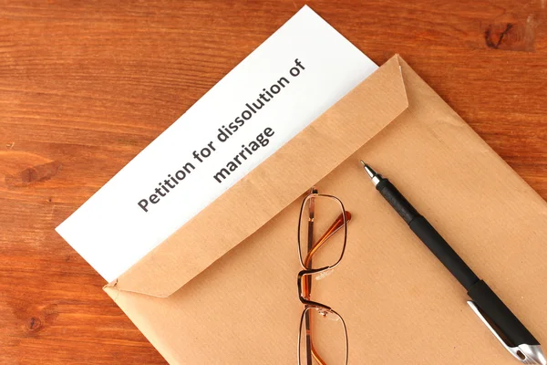 Skilsmisse dekret og kuvert på træ baggrund - Stock-foto