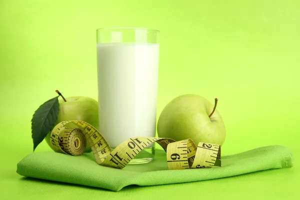 Vaso de kéfir, manzanas y cinta métrica, sobre fondo verde — Foto de Stock