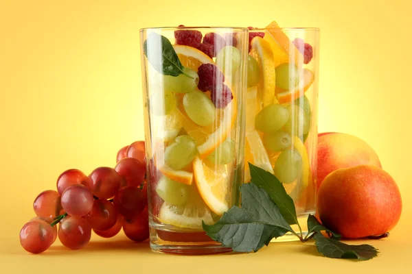 Bicchieri trasparenti con agrumi, su fondo giallo — Foto Stock