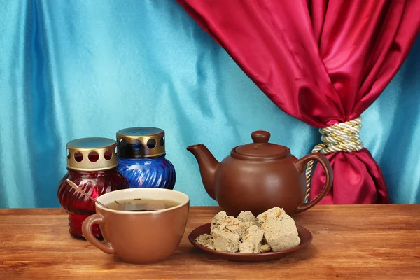 Bule com xícara e pires com halva doce em mesa de madeira em um backgroun — Fotografia de Stock