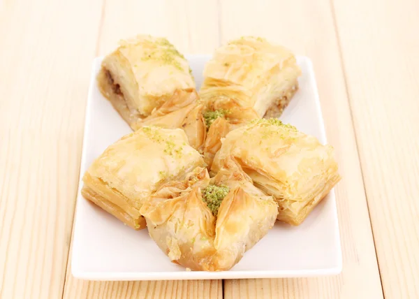 Sweet baklava on plate on wooden background — Stock Photo, Image