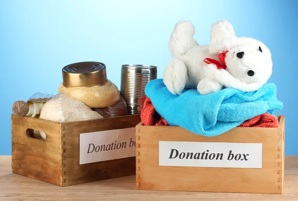 Cajas de donaciones con ropa y comida sobre fondo azul —  Fotos de Stock