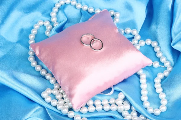 Wedding rings on satin pillow on blue cloth background — Stock Photo, Image