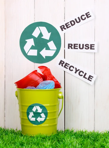 Papelera de reciclaje en hierba verde cerca de valla de madera — Foto de Stock