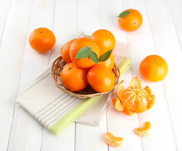 Tangerinas com folhas em uma bela cesta, em mesa de madeira branca — Fotografia de Stock