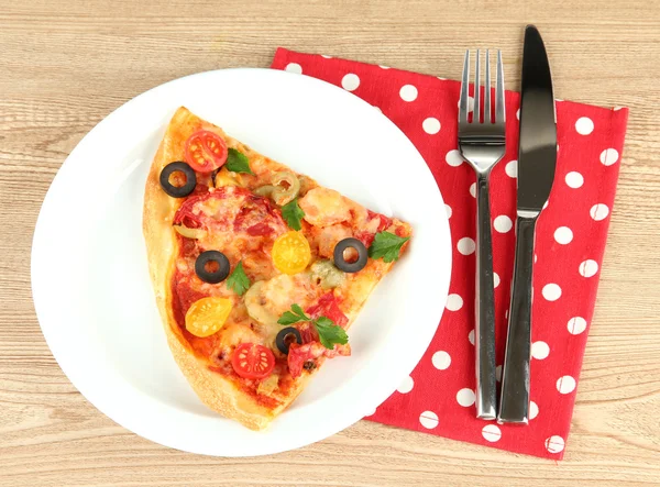 Prato com uma fatia de pizza deliciosa no fundo de madeira — Fotografia de Stock