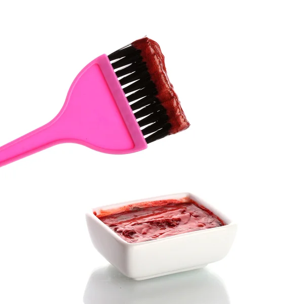 Bowl with red hair color and pink brush, on white background