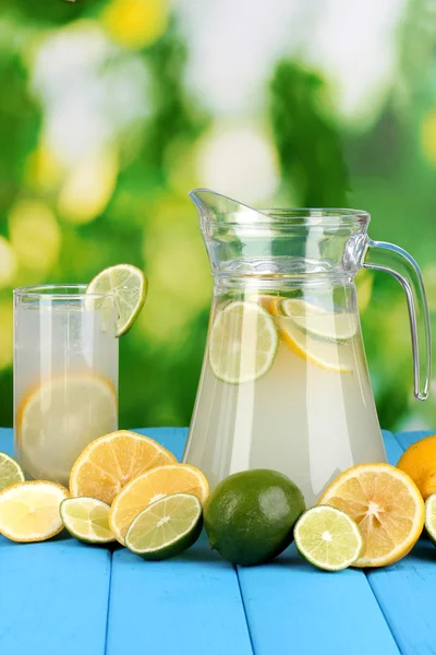 Citrus saft i kannan och glas av citrus runt på naturliga träbord på blå bakgrund — Stockfoto