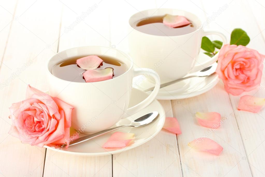 cups of tea with roses on white wooden table