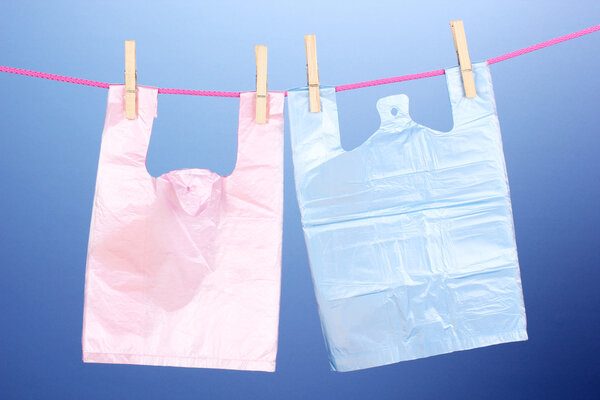 Целофановые мешки висят на веревке на синем фоне
