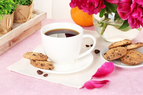 Kopp kaffe, kakor, orange och blommor på bord i café — Stockfoto