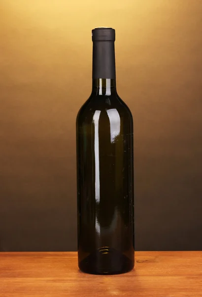 Láhev značkového vína na dřevěný stůl na hnědé pozadí — Stock fotografie