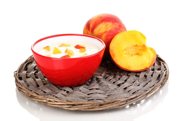 Yoghurt with peach in bowl on wicker mat isolated on white — Stock Photo, Image