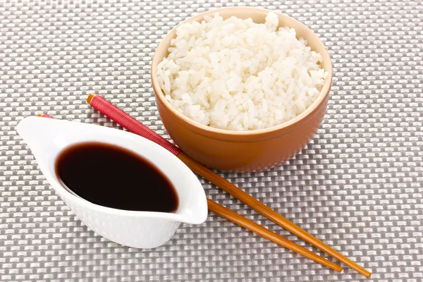 Tigela de arroz e pauzinhos em esteira cinza — Fotografia de Stock