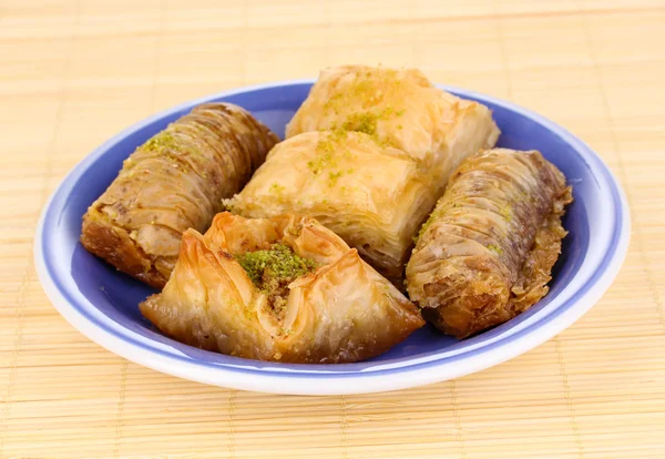 Sweet baklava on plate on bamboo mat — Stock Photo, Image