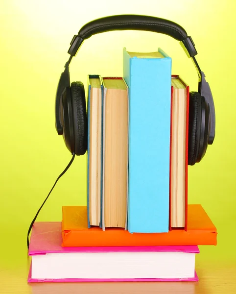 Kopfhörer auf Bücher auf Holztisch auf grünem Hintergrund — Stockfoto