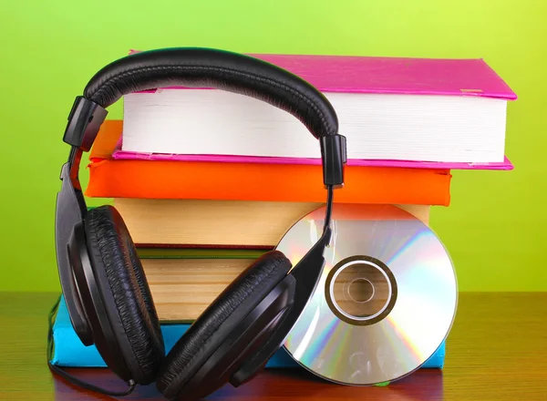 Headphones on books on wooden table on green background — Stock Photo, Image