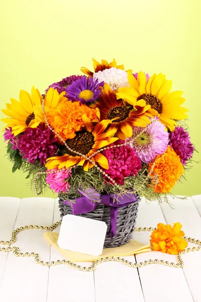 Bellissimo bouquet di fiori luminosi con nota di carta su tavolo di legno su sfondo verde — Foto Stock