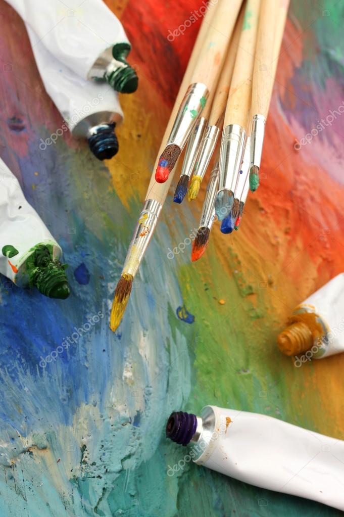 Artist paint brushes and oil paint tubes on wooden palette