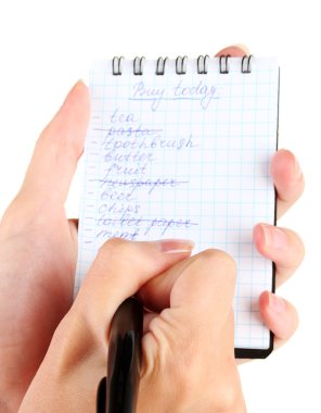 Kadının elinde alışveriş listesi olan bir defter var.