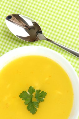 Yeşil masa örtüsü üzerinde beyaz tabak içinde kokulu çorba