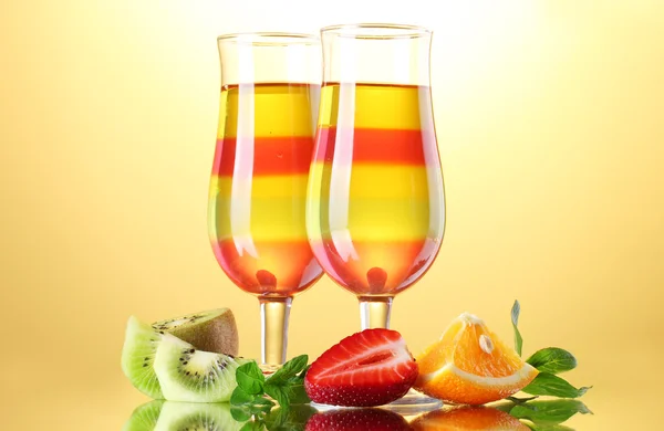 Fruit jelly in glasses and fruits on yellow background — Stock Photo, Image