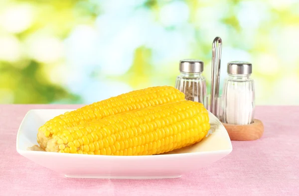 Milho cozido sobre os panos de mesa rosa no fundo da natureza — Fotografia de Stock