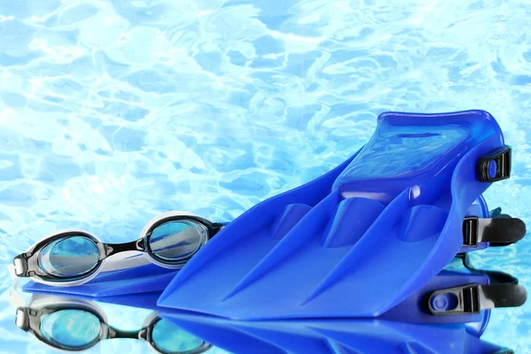 Blue flippers and goggles on blue sea background — Stock Photo, Image