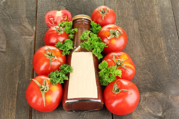 Ketchup in bottle and tomatoes on wooden table — Stock Photo, Image