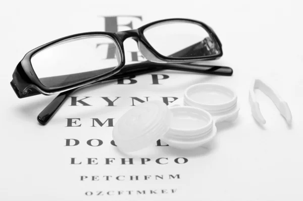 Gafas, lentes de contacto en recipientes y pinzas, sobre fondo de carta de ojos snellen — Foto de Stock