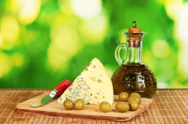 Composition of blue cheese and olives on bright green background close-up — Stock Photo, Image