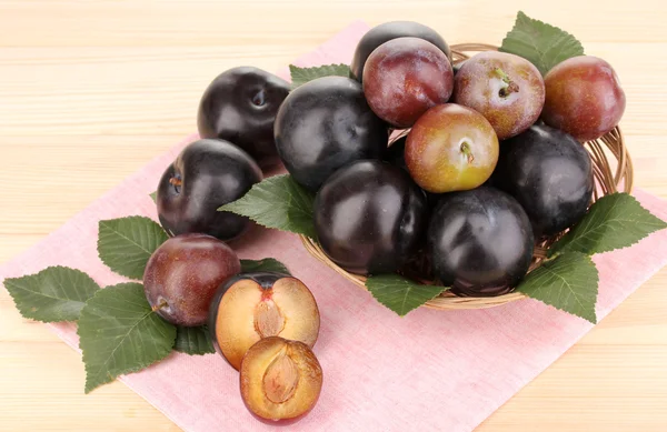 Rip plums on basket on wooden table — Stock Photo, Image
