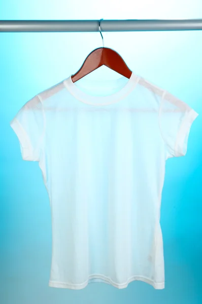 White t-shirt on hanger on blue background — Stock Photo, Image