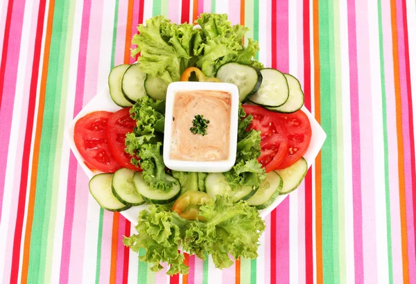 Нарезанные овощи и соус на тарелке на полосатой скатерти — стоковое фото