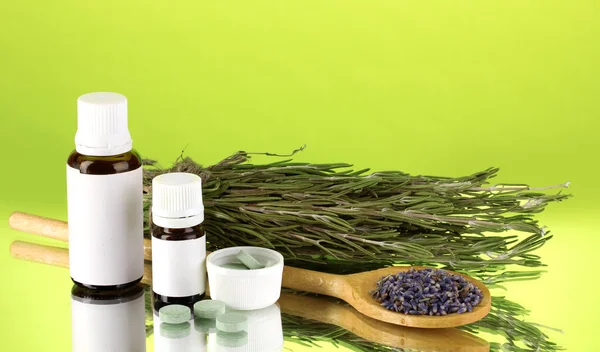 Frascos de medicamentos y hierbas sobre fondo verde. concepto de homeopatía — Foto de Stock