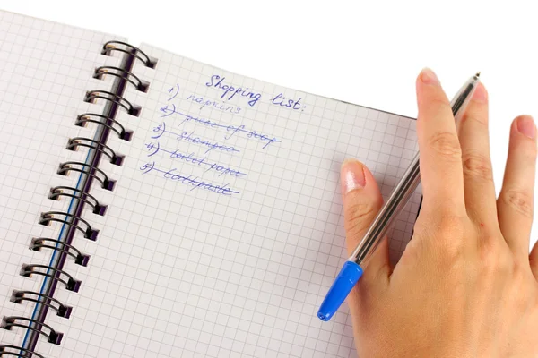 Die Hand einer Frau hält ein Notizbuch mit einer Einkaufsliste in Großaufnahme — Stockfoto