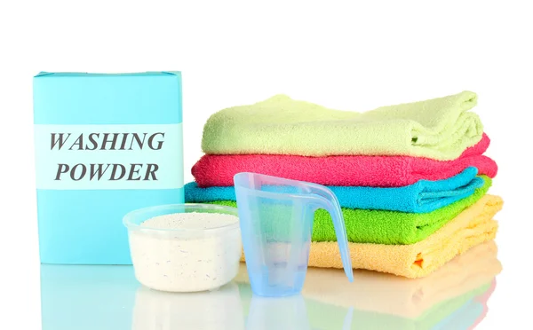 Box of washing powder with blue measuring cup and towels, isolated on white — Stock Photo, Image