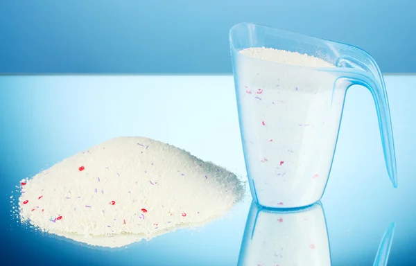 Washing powder in a measuring cup, on blue background close-up — Stock Photo, Image