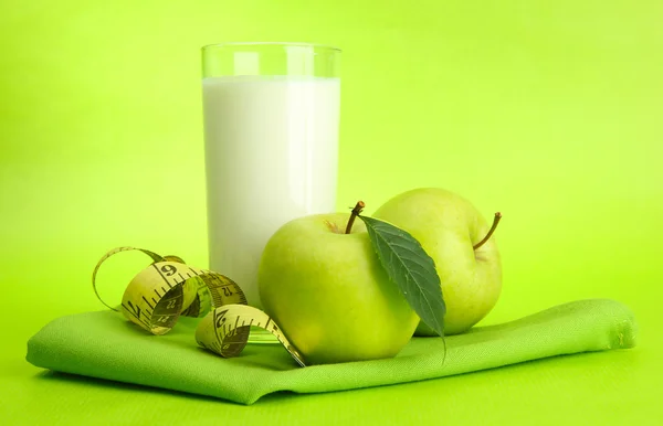 Glas kefir, äpplen och måttband, på grön bakgrund — Stockfoto