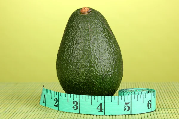 Avocado con nastro di misurazione su sfondo verde — Foto Stock