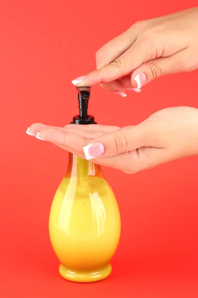 Woman squeezing lotion on her hand, on red background close-up — Stock Photo, Image