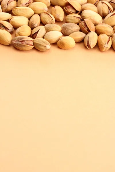 Tasty pistachio nuts, on beige background — Stock Photo, Image