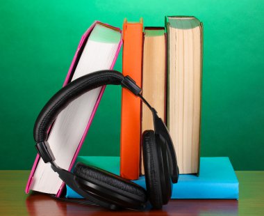 Turkuaz zemin üzerine ahşap masa kitap üzerinde kulaklık