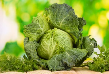 Fresh savoy cabbage on wooden table on natural background