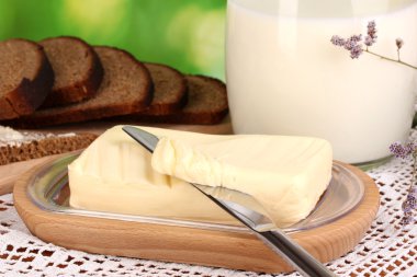Doğal arka planda ekmek ve sütle çevrili ahşap tutacağa tereyağı.