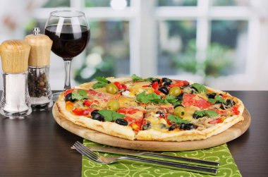 kadeh kırmızı şarap ve baharat üzerine ahşap masa üstünde pencere ile lezzetli pizza
