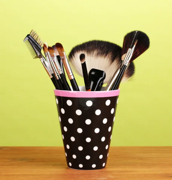 Makeup brushes in a black polka-dot cup on yellow background — Stock Photo, Image