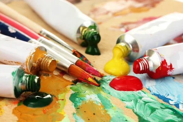 Abstract acrylic paint, paint tubes and brushes on wooden palette — Stock Photo, Image