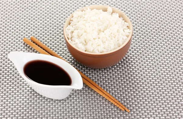 Cuenco de arroz y palillos en estera gris — Foto de Stock